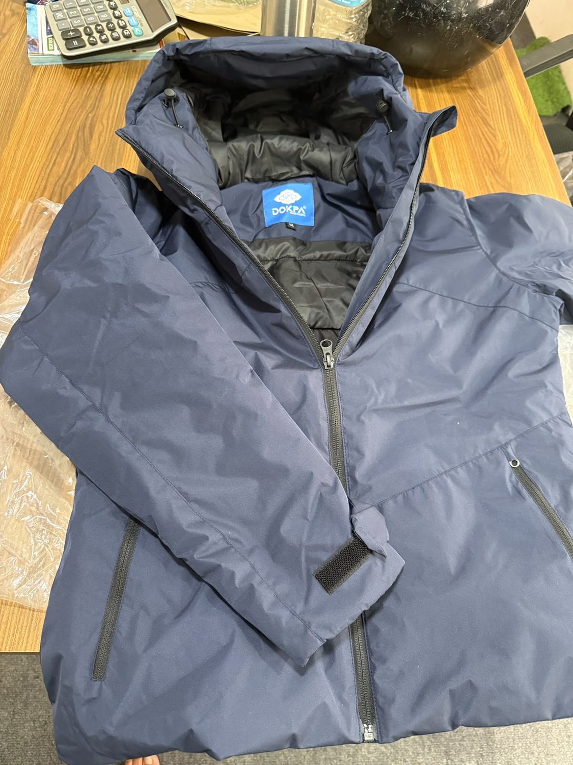 A navy jacket collar opened on a wooden table with the blue Dokpa label and a small M tag stitched inside it